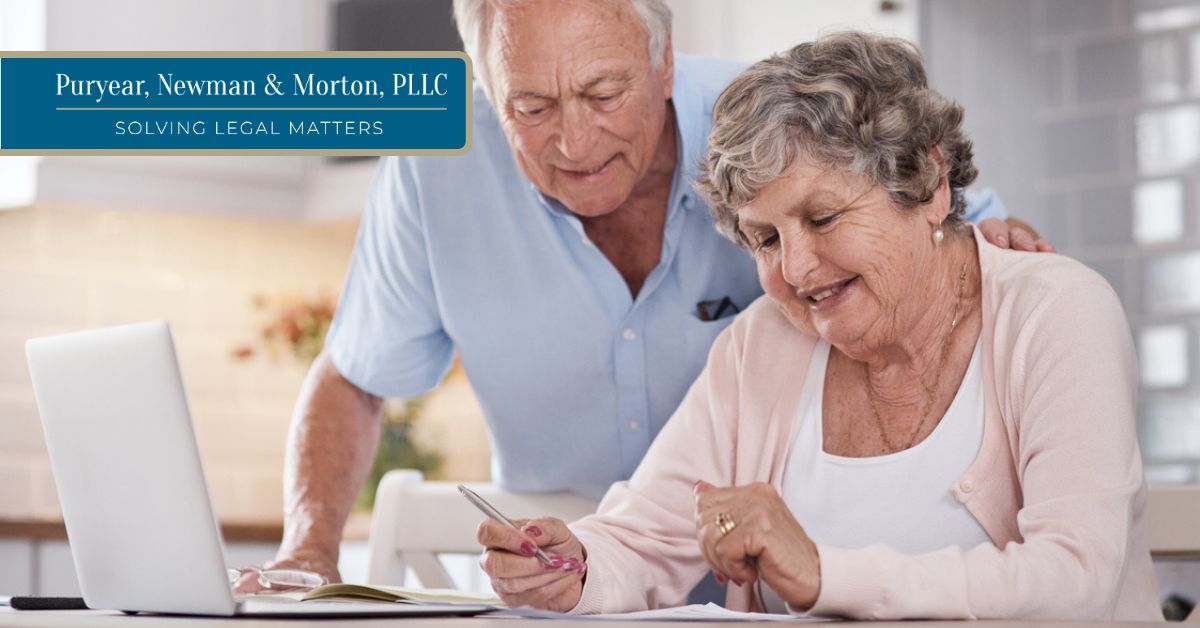 Older couple reviewing documents with a laptop nearby